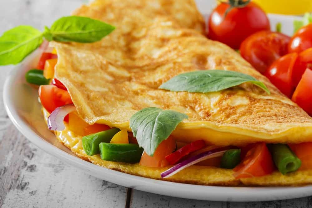 a tasty vegetable omelet with cherry tomatoes on the side.